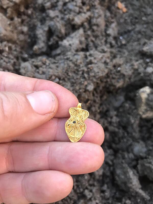 Grabungsmitarbeiterin Bea Koens zeigt den von ihr gefundenen, frühmittelalterlichen Goldanhänger (Foto Bea Koens).