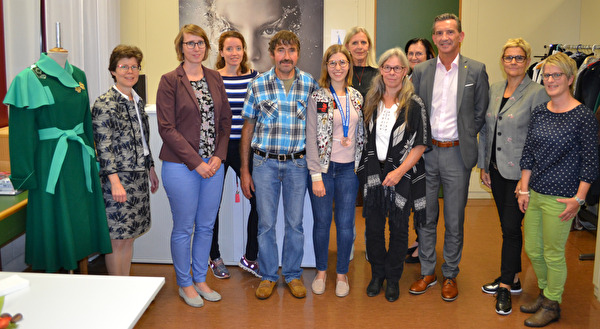 Bei der Ehrung im Lehratelier: (von links) Yvonne Slongo, Vorsteherin Amt für Berufsbildung, Nicole Leyssing-von Ah, Expertin Swiss Skills Team, Nadine Brand, Vereinsvorstand, Alois Stöckli, Vater, Diplomgewinnerin Denise Stöckli, Annalise Russi, Präsidentin des Vereins Lehratelier für Beklei-dungsgestalterInnen, Bea Stöckli, Mutter, Dorothea Michel, Vereinsvorstand, Regierungsrat Beat Jörg, Gerda Walker, Atelierleiterin, und Barbara Infanger, Vereinsvorstand. Links im Bild der an den World Skills von Denise Stöckli in 12,5 Stunden angefertigte Mantel. 