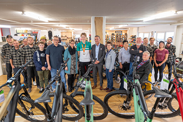 Familie und Belegschaft gratulieren zum Erfolg: (vorne von links) Christian Gisler, Inhaber Bikewelt Gisler GmbH, Bruder Noel mit Eltern Beat und Fabienne Muoser, Medaillengewinner Lars Muoser, Bildungs- und Kulturdirektor Beat Jörg und Yvonne Slongo, Leiterin Amt für Berufsbildung.