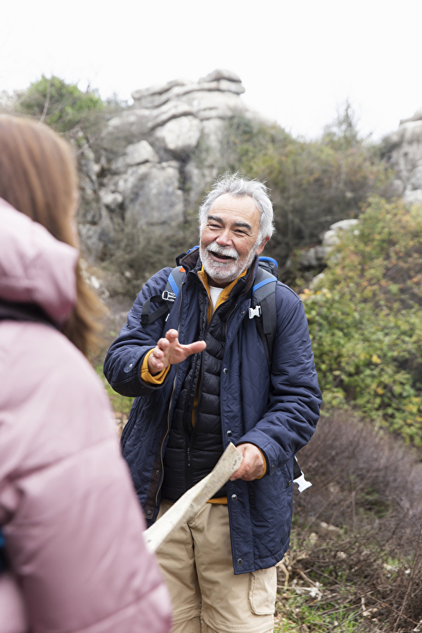 Mann im Pensionsalter in Wanderkleidung draussen mit Karte in der Hand und im Gespräch mit einer Frau.