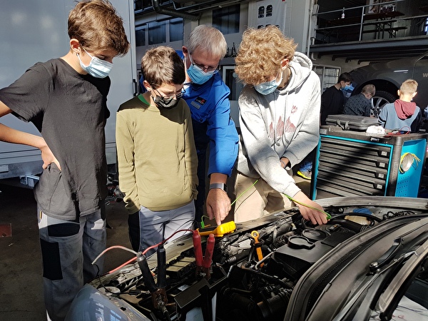Der Berufsbildner der Garage Windlin AG, Kerns, prüft mit Schülern den Motor eines Autos