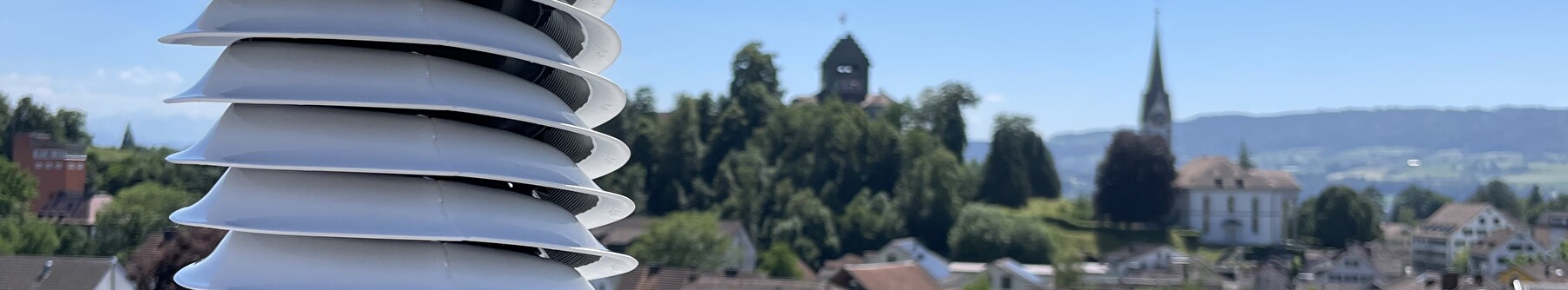 Blick über Uster mit der Kirche und Burg im Hintergrund und einem Klimasensor im Vordergrund