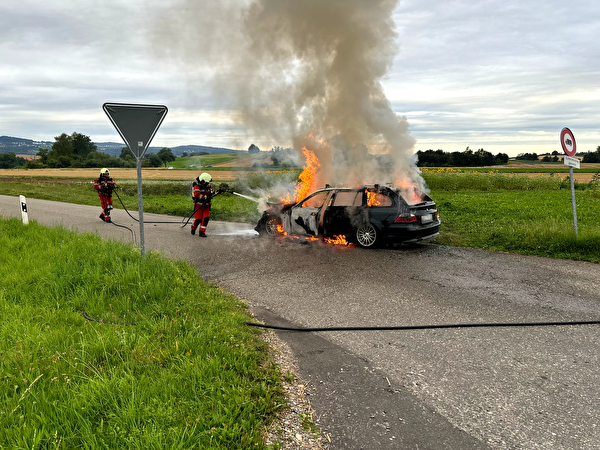 Fahrzeug steht in Brand und wird durch Feuerwehrleute gelöscht.