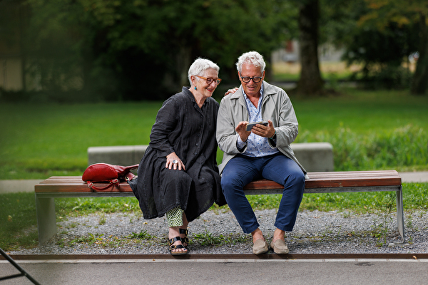 Zwei ältere Menschen sitzen auf einer Bank imStadtpark