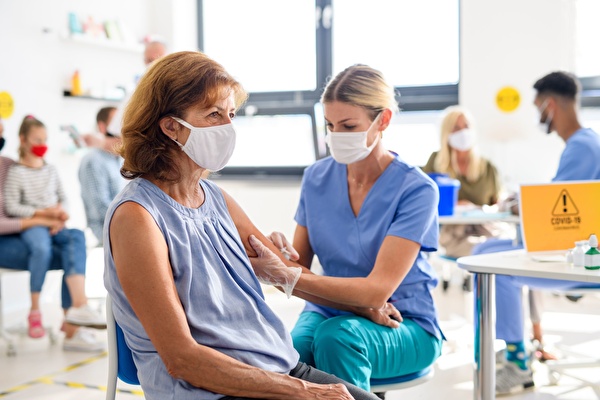 Frau wird von med. Fachperson geimpft