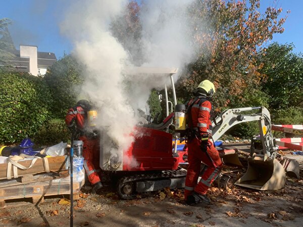 Angehörige der Feuerwehr bei Löscharbeiten an einem Bagger