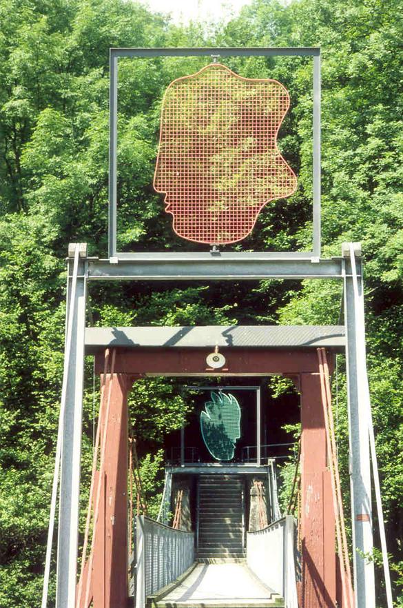 Hans Anliker, Schinznach
(Ankauf Kulturwegstiftung)

Gespräche über den Fluss
Gespräche über die Brücke
also nicht unüberwindbare Gespräche zwischen Mann und Frau
Die auf dem Brückenkopf stehenden
Eisenrahmen sind Träger zweier Gesichter in Wettingen die Frau 
In Neuenhof der Mann
Die Köpfe sind um die eigene Achse drehbar und bewegen sich im Wind
Manchmal schauen sie sich an
Manchmal kehren sie sich weg und wollen nichts voneinander wissen.


Material: Eisen bemalt