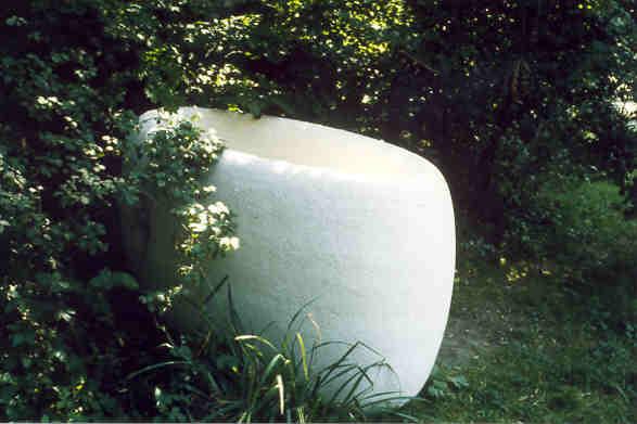 Heiner Richner, Basel
(gestiftet durch die Schweizerische Bankgesellschaft)

In der Auenlandschaft, im Restwasser unterhalb des Spinnereiwehres, liegen Hunderte von Steinen, unregelmässig in der Form, grob die einen vom Wasser glatt geschliffen die andern. Nahe am Ufer, selten nur vom Wasser umspült, liegt ein exakter , glatter Steinring. Kein Kreis, sondern eine ausgehöhlte Ellipse, Natur- und Kunstform in sich vereinigend. Sein Einfügen in die Situation, das kaum wahrnehmbare Spiegeln des Wassers auf den gebogenen Flächen und gleichzeitig das deutliche Fremdsein der präzisen Form geben dem Steinring Spannung und Wirkung.

Material: Comblanchien-Kalkstein