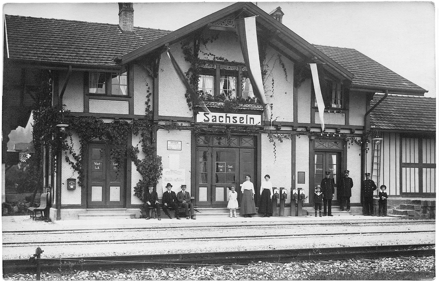 Die Aufnahme stammt aus der Zeit vor dem 1. Weltkrieg. Damals gab es noch getrennte Wartesäle für die verschiedenen Klassen und einen Stationsvorstand mit mehreren Mitarbeitern (rechts im Bild).