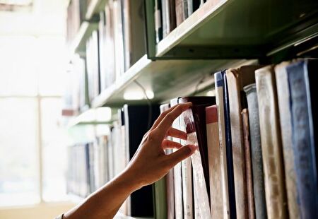 Hand, die Bücher aus einem Büchergestell nimmt