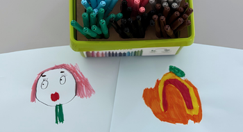Zwei Kinderzeichnungen und eine bunte Filzstiftbox
