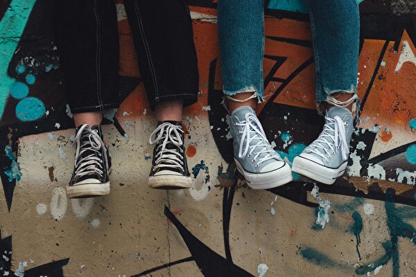 Lehrstellen 2027: 2 Jugendliche die auf einer Mauer sitzen, Graffiti-Mauer, converse Schuhe