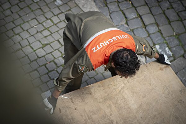 Symbolbild Zivilschtutz: Zivilschutzdienstleistender hebt eine schwere Holzplatte
