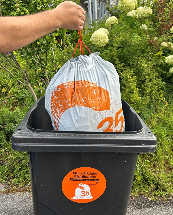 Gebührensack wird in Container entsorgt