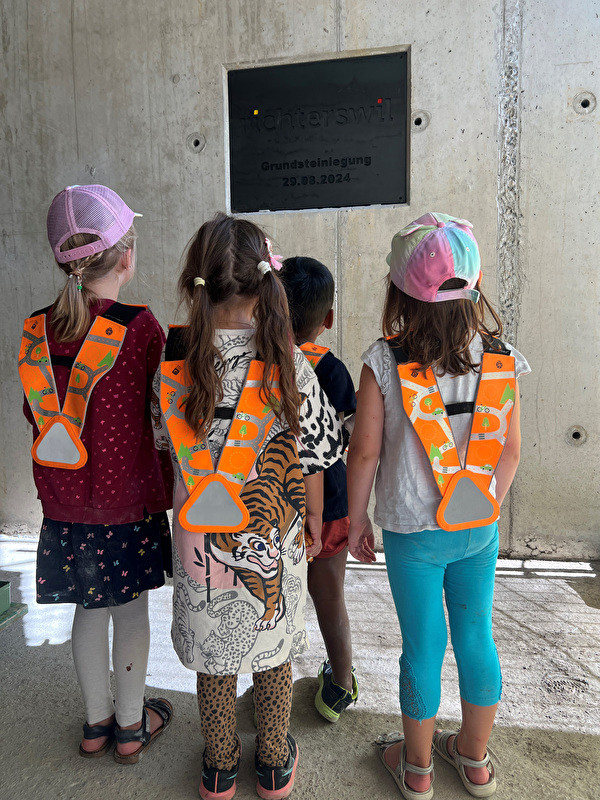 4 Kindergartenkinder stehen vor der Zeitkapsel, die anlässlich der Grundsteinlegung zum Feuerwehrgebäude inklusive Kindergarten befüllt und in die Wand eingelassen wurde