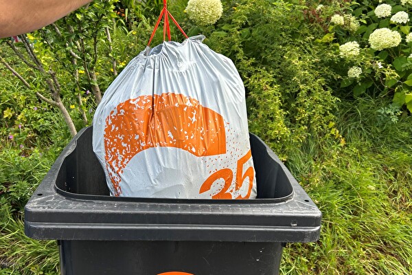 mann wirft abfallsack in kunststoffcontainer