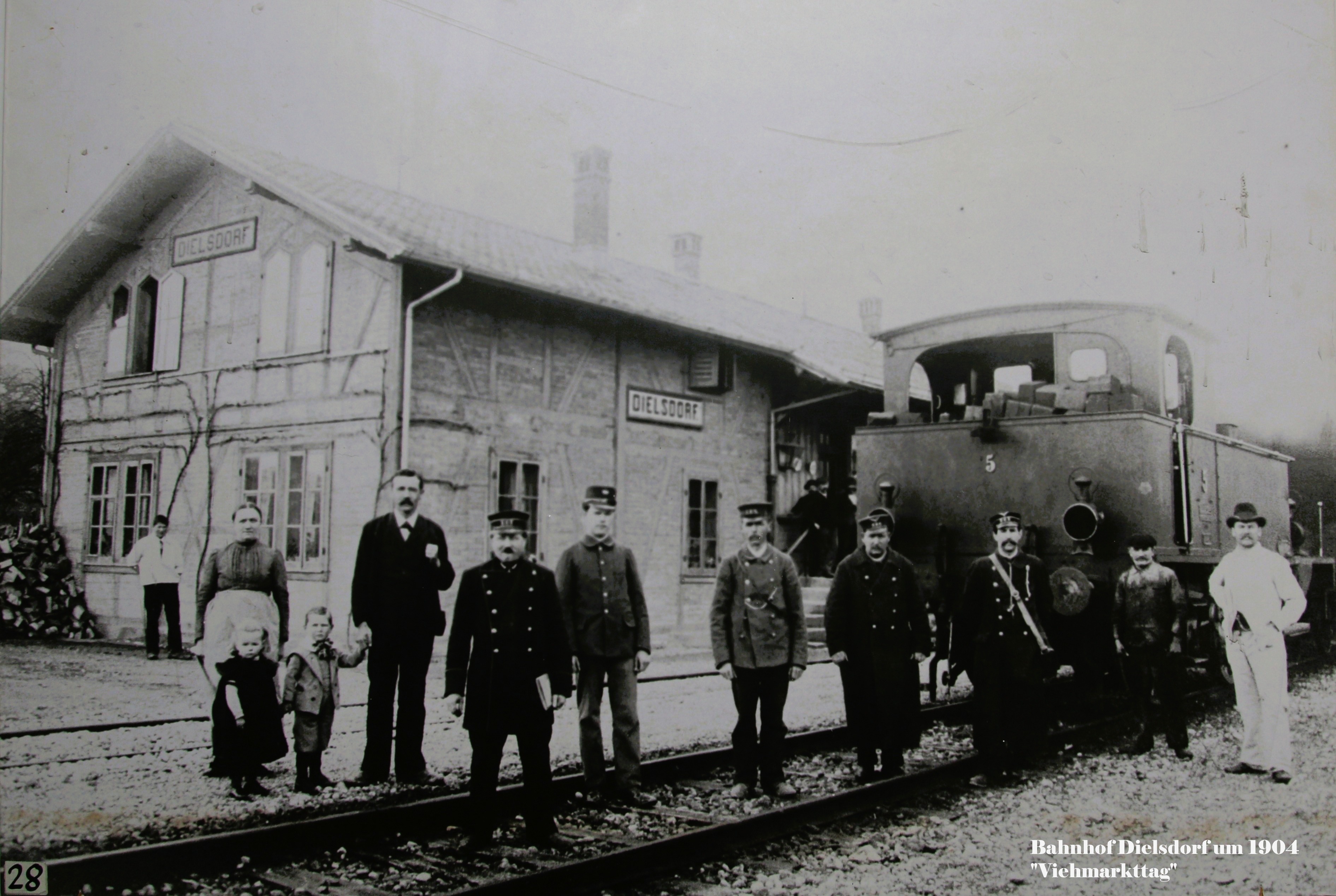 Bahnhof Dielsdorf, um 1904, von Südosten. Viehzug an einem Viehmarkttag vor der Abfahrt; mit Bahnpersonal, Restaurant "Bahnhofgarten", Postbote und Metzgerbursche. Auf der Rampe Chemiker Maag
