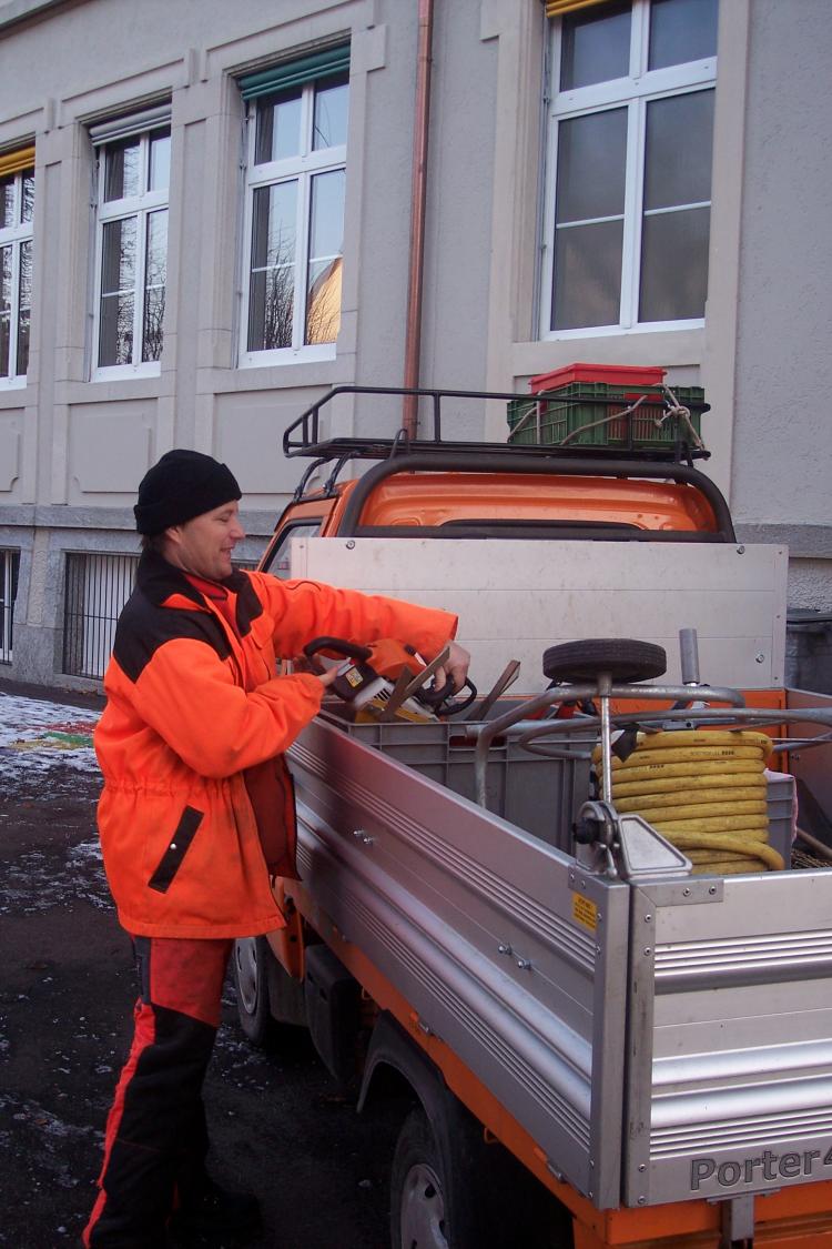 Mitarbeiter der Abteilung Betriebe in orangen Arbeitskleidern versorgt Wasserschlauchrolle auf dem Gemeindefahrzeug