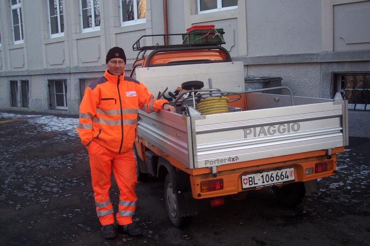 Mitarbeiter der Abteilung Betriebe in orangen Arbeitskleidern versorgt Wasserschlauchrolle auf dem Gemeindefahrzeug