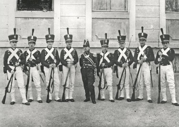 Der Turnverein spielt an der Fasnacht eine Stänzlergruppe anno 1803 aus. Die Gruppe steht vor dem Breiteschulhaus.

Datierung: 1927