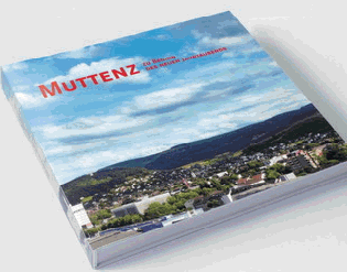 Quer liegendes Gemeindebuch mit Foto von Muttenz und stark bewölktem Himmel