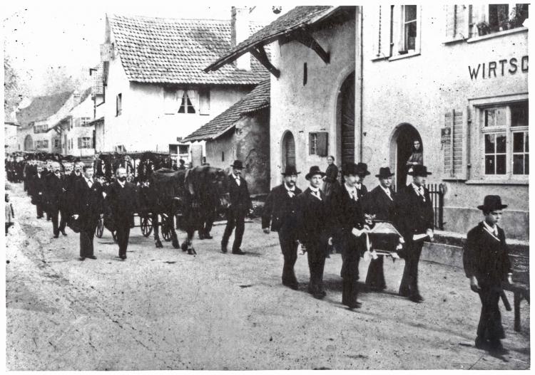 Trauerzug durch die Burggasse, rechts die Wirtschaft zum Schlüssel

Datierung: 12. Oktober 1904