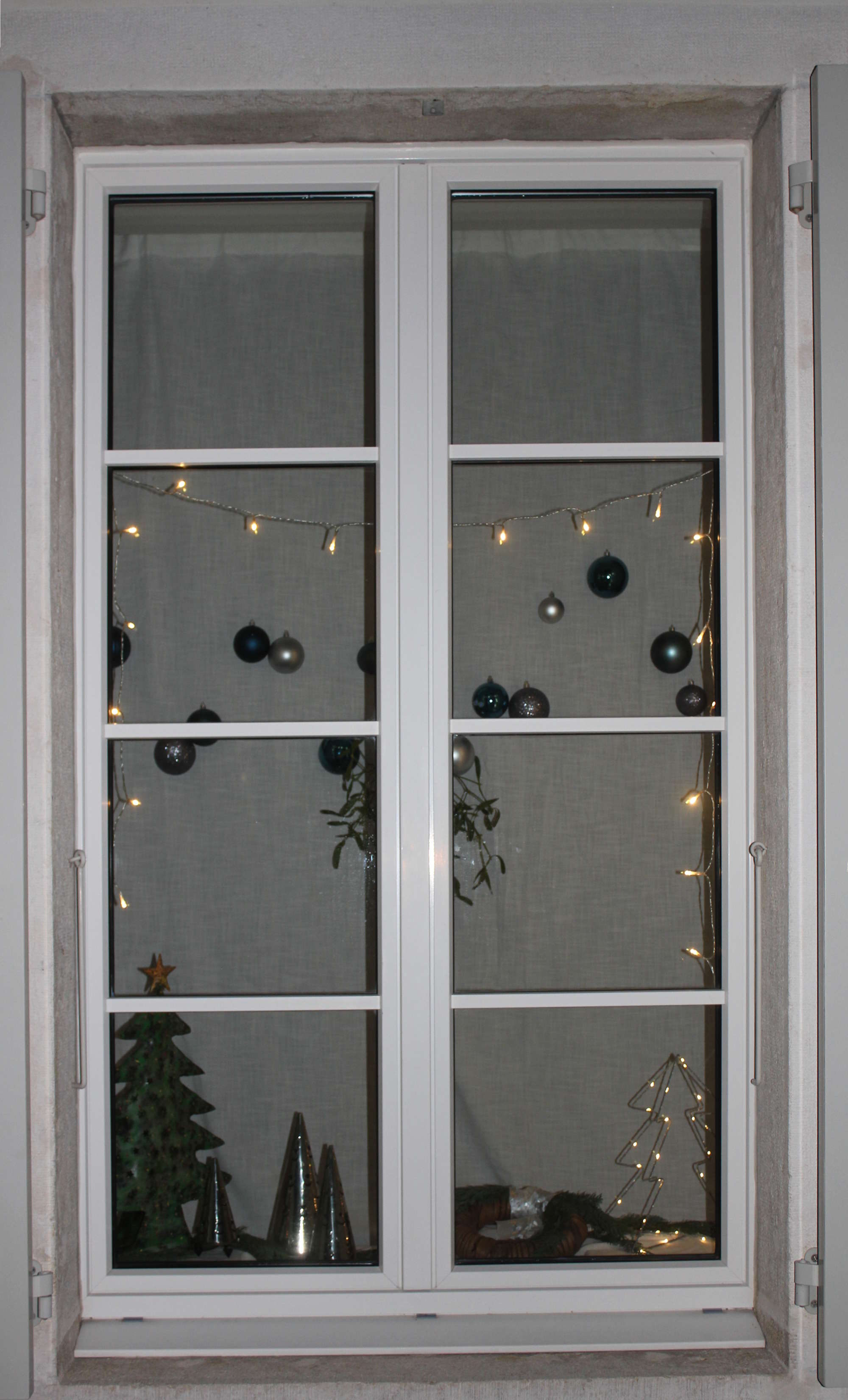 Adventsfenster mit Licht, Bäumen und Kugeln