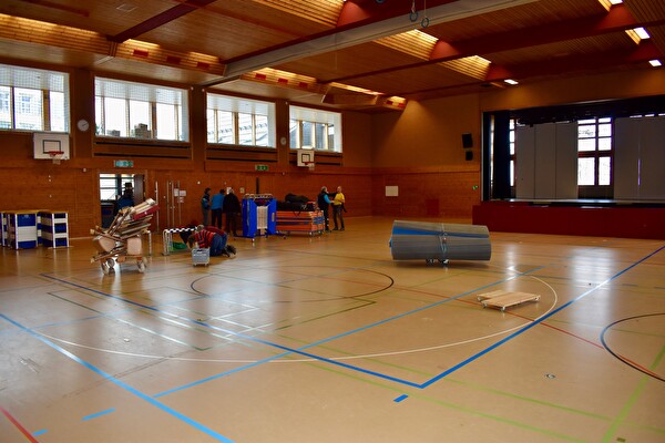 Vereinsmitglieder und Lernende räumen mit dem Hauswartteam die Turnhalle aus