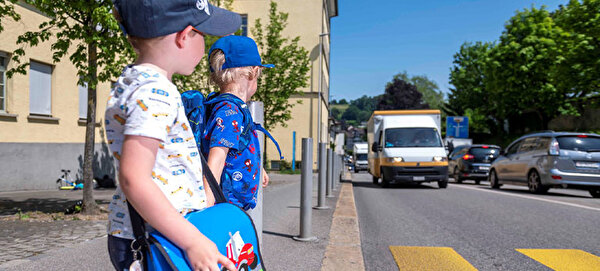 Zwei Schulkinder stehen an einem Zebrastreifen.