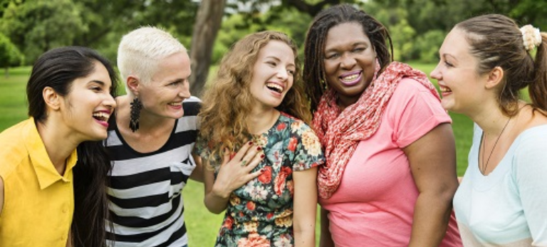Mehrere Frauen verschiedener Ethnien lachen zusammen.