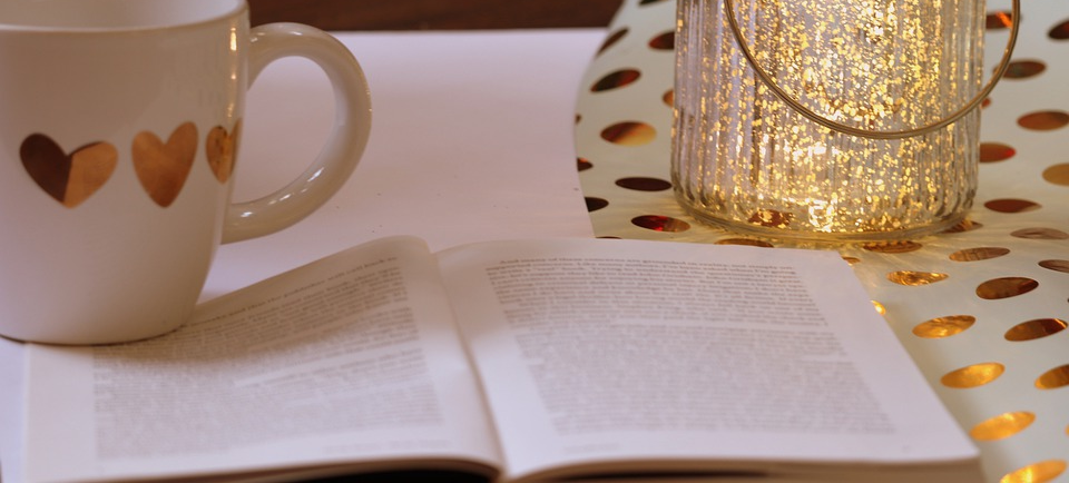 Buch und Kaffeetasse auf einem Tisch.