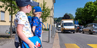 Zwei Schulkinder stehen an einem Zebrastreifen.
