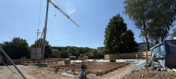 Die Baustelle der neuen Schulanlage Eyfeld mit Kran und Bauelementen.