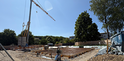 Die Baustelle der neuen Schulanlage Eyfeld mit Kran und Bauelementen.