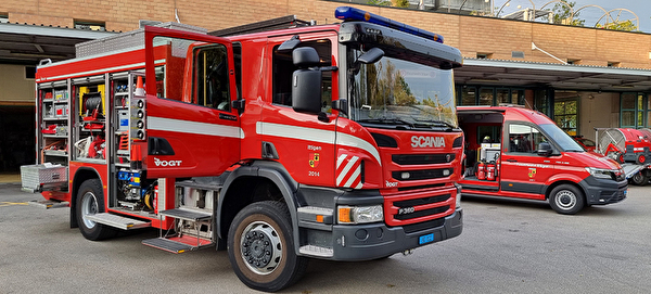 Zu sehen sind verschiedene Feuerwehrfahrzeuge auf einem betonierten Vorplatz.
