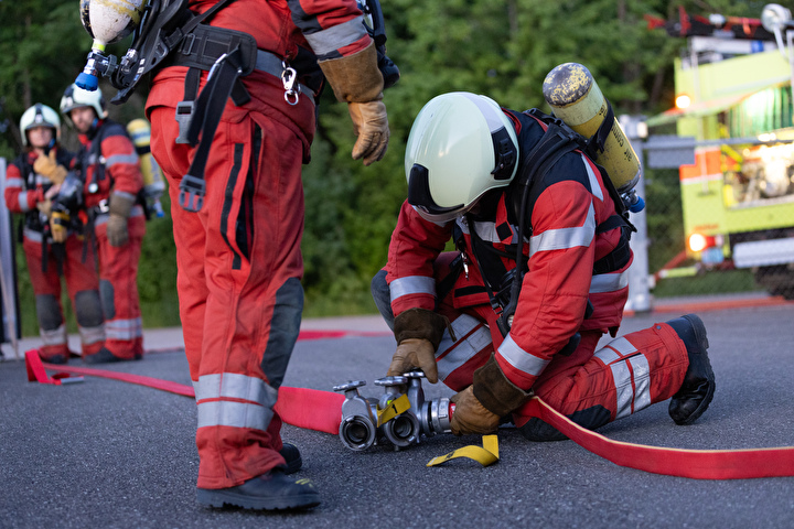 Bild eines Feuerwehrmannes mit einem Schlauch am Boden