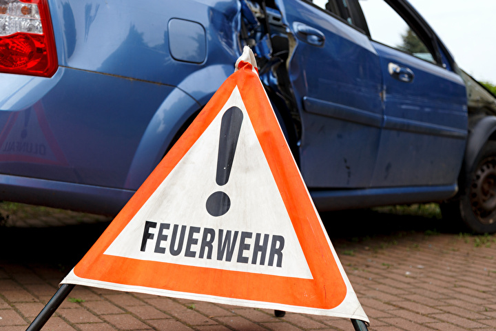 Symbolbild mit einem defekten Fahrzeug und einem Feuerwehr Warnschild