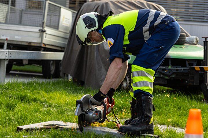 Bild eines Feuerwehrmannes mit einem Seitenschleifer mit dem er ein Stück Metall schneidet