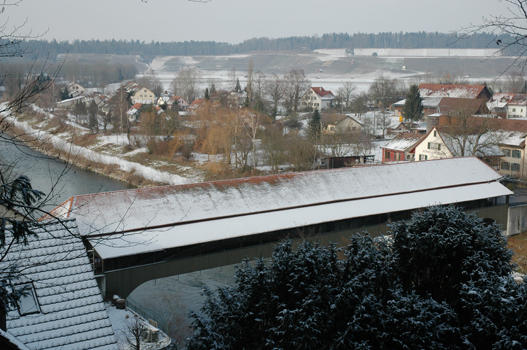 Hinter dem Pavillon geht es nach ein paar Treppenstufen auf dem Waldweg hinunter in den extensiven Teil des Parks. Unvermittelt erhalten wir einen lohnenden Ausblick auf die alte Holzbrücke, die Thur, Kleinandelfingen und den Schiterberg.