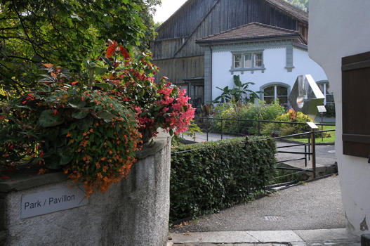 An der abgeschrägten Ecke des Pförtnerhauses findet sich der etwas versteckte Zugang zum Schlosspark. Hier beginnt der Promenadenweg über dem Abgrund des Tobels und führt an der ehemaligen Orangerie vorbei.