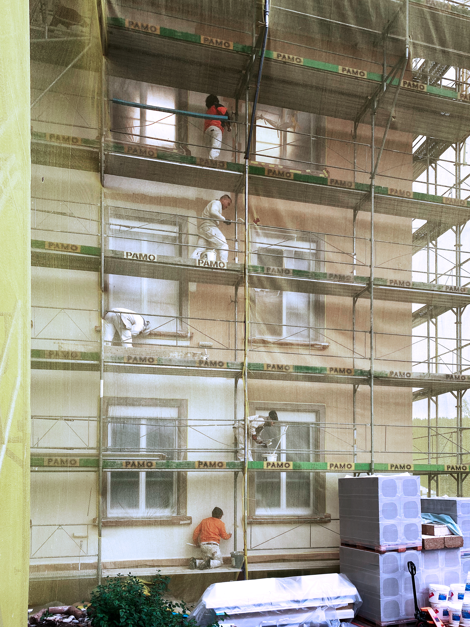 Okt. 2020
Nach der vollendeten Ziegeleindeckung des Hauptdachs kann die Fassade gestrichen werden. Noch kann die neue Fassadenfarbe lediglich durch das gelbe Netz erahnt werden.