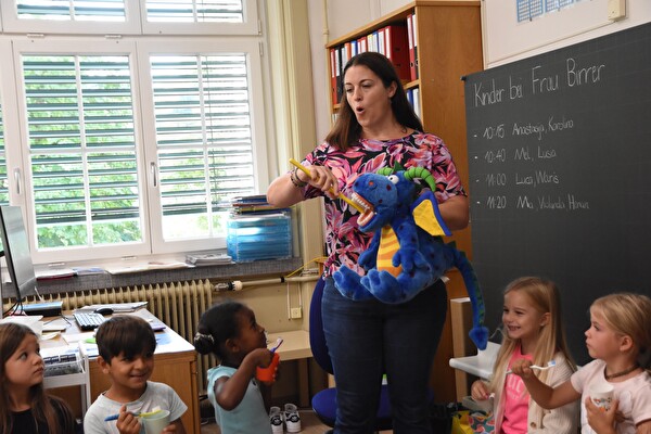 Regina Bruderer-Schnelli und Drache Eddie leiten die Kinder bei der Zahnreinigung an.