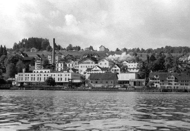 1856 übernimmt Michael Weber die 1826 von Heinrich Rusterholz gegründete Brauerei und führt sie unter eigenem Namen weiter. Auf dem Bild sind das Brauereigebäude, der Hochkamin sowie das Sudhaus zu sehen. Aufnahme für die Jubiläumsbroschüre zum 100jährigen Bestand der Brauerei, 1956.