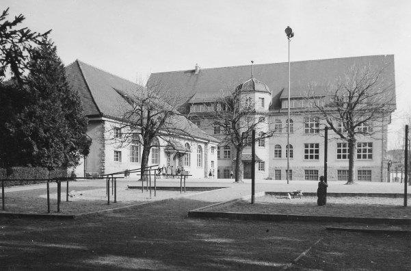 Auf dem Bild ist das - 1909 eingeweihte - Schulhaus Glärnisch, mit der Turn- und Konzerthalle, dem Pausenplatz sowie der Sportanlage, von Westen her zu sehen. Das Bild entstand um 1950.