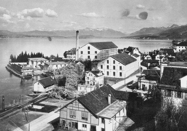 Blick auf das Giessenhorn mit den Gebäuden der Tuchfabrik Pfenninger. Das grosse vierstöckige Gebäude mit der Heizzentrale wurde 1906 durch Robert Maillart (1872-1940) in Beton erbaut. Das kleine Haus in der Mitte gehörte dem Baumeister Cavallasca. Dieses musste 1936 der Verbreiterung der Seestrasse weichen. Bild um 1908, Vorlage für eine Postkarte.