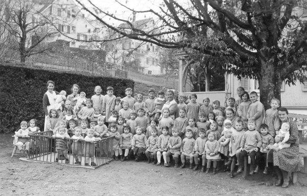 Die Kinderkrippe Wädenswil wurde 1898 gegründet. Im Jahr 1906 zog sie in das Gebäude an der Etzelstrasse 6, wo sie sich heute noch befindet. Das Bild entstand 1941 vor dem Gebäude an der Etzelstrasse 6. Damals besuchten rund 60 Kinder die Krippe. In der Mitte mit Haube Schwester Rosa Brunner.