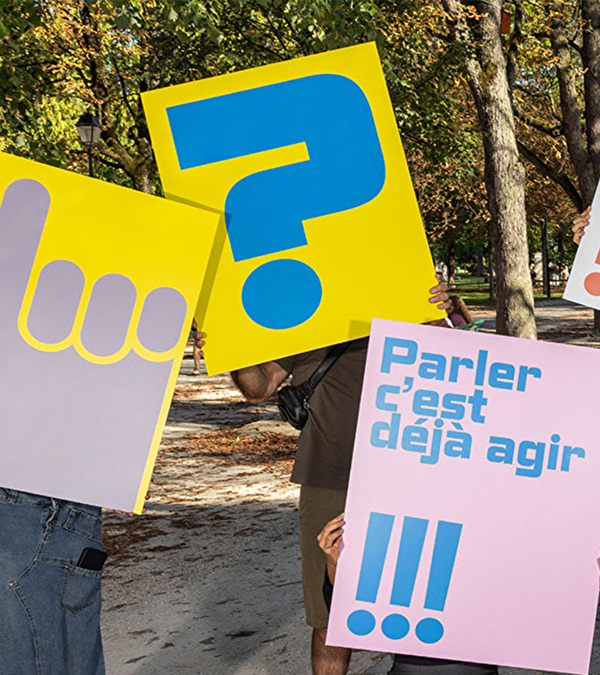 panneaux d'information colorés tenus par des gens pour annoncer que parler c'est déjà agir