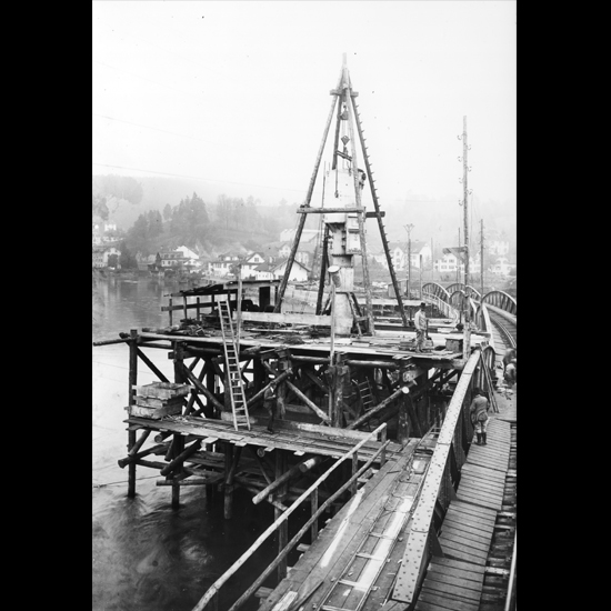 Auf dem Bild ragt aus dem Gerüst der Kamin mit der aufgehängten Druckkammer hervor und verrät den darunter liegenden Caisson. Er wird das Fundament des Pfeilers bilden.