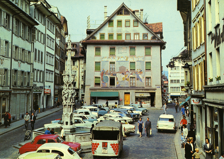 Fussgänger/innen zwischen abgestellten Autos auf dem Weinmarkt um 1960.