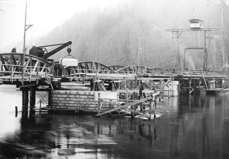 Am Kranwagen auf der Ersatzbrücke: Ein Teil des Pfeilerkopfs (Auflagerträger) für den linken Pfeiler. Inzwischen war mit dem fahrbaren Portalkran ein erstes Element des Oberbaus aufgerichtet worden.